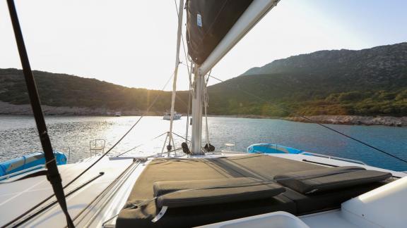 The foredeck of a Lagoon 560 catamaran features comfortable sunbeds overlooking the sunset over the calm, turquoise wate